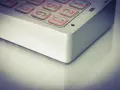 Zbliżenie na klawiaturę domofonu z podświetlanymi na pomarańczowo przyciskami z cyframi.